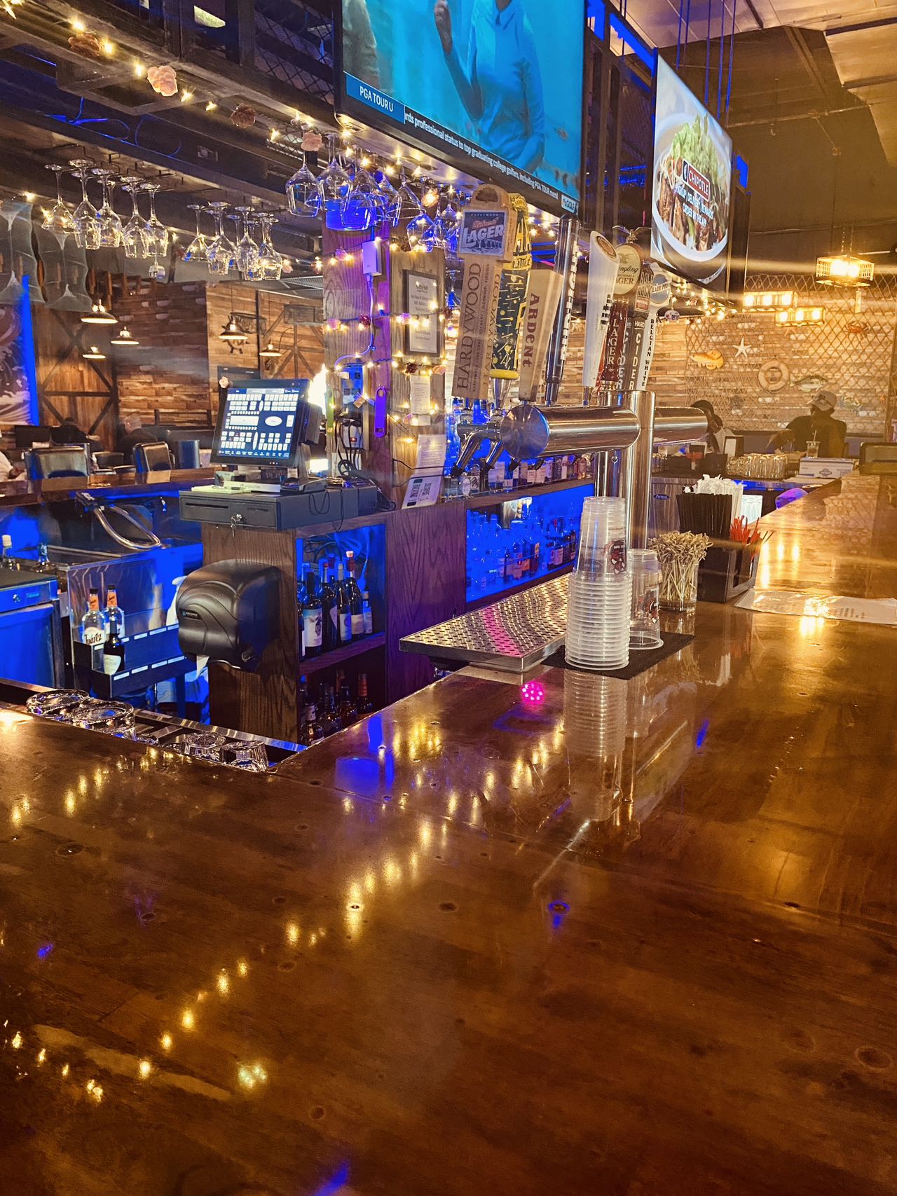 Full bar with draft taps, hanging wine glasses, and blue lighting at Boil Bay